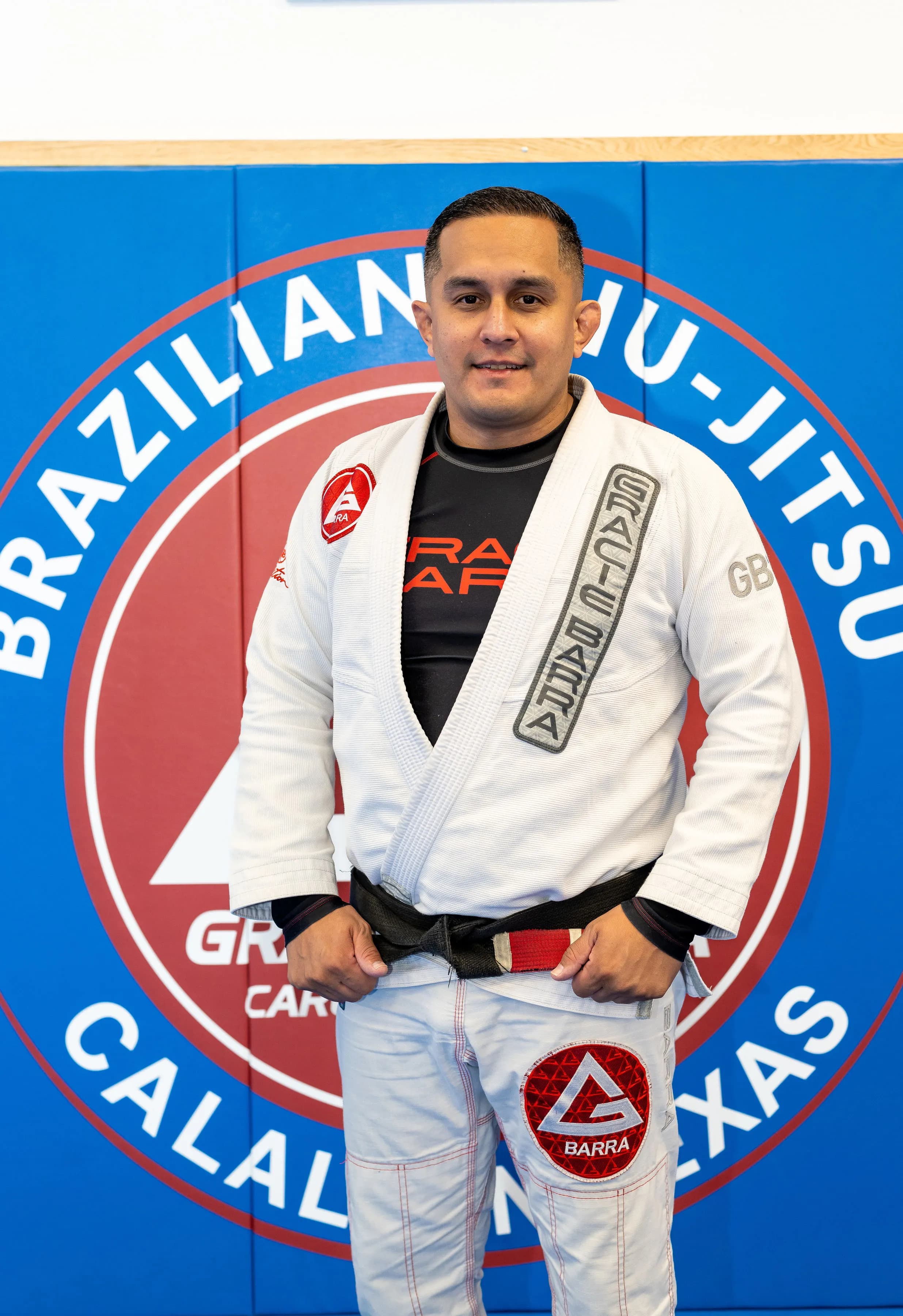 Gracie Barra Calallen black belt instructor in front of the academy logo in Corpus Christi